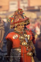 Image du Maroc Professionnelle de  Le porteur d'eau dit –Guerrab- est visible au milieu de la foule, avec sa tenue folklorique et son chapeau multicolore, chargé de coupelles en cuivres ou de fer blanc qui brille sous les rayons du soleil. Ces hommes sont une des attractions de la Place Jemaa El Fana à Marrakech et passent souvent leur temps à poser pour la photo souvenir aux touristes contre quelques pièces en retour, 25 Janvier 2002. (Photo / Abdeljalil Bounhar)